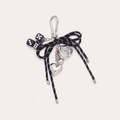Detail of woven bow keychain with silver rose, dice, and metallic hearts on grey backdrop - Black Punk Dice Rose Style