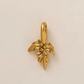 Détail du pendentif fleur en forme de houx doré montrant la texture brossée et l'attache - Pendentif Fleur de Décembre