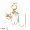 Detailed view of fashion keychain with golden croissant charm and pearl bead accents - Croissant Theme