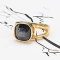 Vue macro d'une bague vintage dorée avec une pierre noire carrée et texture spirale - Or Noir