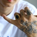 Dettaglio anello vintage da uomo in oro con grande pietra nera ovale e decori a sbalzo - Agata nera dorata