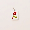 Detailed close-up of a 18K gold-plated rectangle charm with red flower and heart patterns - Flower