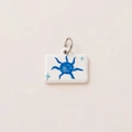 Detail view of rectangular white pendant with blue sun and green star motifs - Sun Pendant