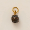 Macro shot of faceted tiger eye stone pendant with a polished golden ring attachment - Olive Green Pendant Style