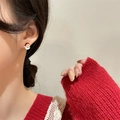 On-ear view of cute red Santa Claus stud earrings with gold trim and white beard detail - Santa Claus