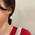 Close-up of a festive red and white gift box stud earring worn by a model in winter - Christmas Gift