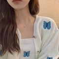 Primer plano del collar con colgante de corazón dorado con cárdigan blanco de mariposa - Rosa oro