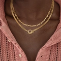 Detailopname van gelaagde gouden kettingen met OT-sluiting op een roze gebreid vest - Gouden Curb Ketting OT Sluiting (XL1080-17)