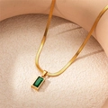 Macro shot of gold snake chain necklace with emerald rectangular gem on sand - Emerald Green Rectangle Necklace