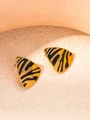 Macro shot of gold-plated triangle earrings with black zebra stripes on a textured surface - Triangle Zebra Print Earrings