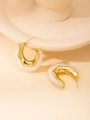 Close-up of minimalist gold U-shape earrings with white resin inlay on a ceramic stand - C-shaped Fluid Earrings (#4 White)