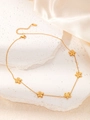 Vue macro d'un collier doré à pétales avec bords perlés sur pierre et soie - Fleur à Cinq Pétales