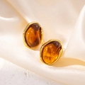 Macro detail of irregular drop earrings with gold metallic frames and amber resin stone - Oval Amber