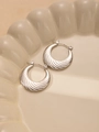 Dettaglio di orecchini a cerchio croissant argento con trama a spirale su vassoio beige - Stile Croissant a Spirale (#0237)