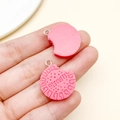 Pink resin Oreo-style biscuit pendant with bite mark and metal ring held in hand - Rose Red