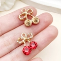 Pendentif cerise avec pierres rouges et détail de nœud papillon scintillant - Cerise Nœud Papillon Strass Rouge Or KC (23423) / 17x14x6mm