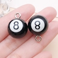 Paar zwarte hars biljartbal hangers nummer 8 met zilveren metalen ringen getoond in hand - Zwarte hars poolbal nummer 8 / 21x16x16mm