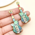 Handheld view of colorful acrylic guitar pendants for DIY jewelry and keychains - Green Double-sided Printed Guitar (24039) / 48x16x2mm