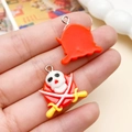 Hand holding pirate skull resin pendant with yellow swords for DIY jewelry making - Red Skeleton Pirate (24224) / 22x22mm
