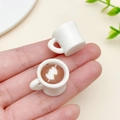 Miniature resin coffee cup pendants with latte art shown in hand for scale - White 3D Arrow Through Heart Style (23962)