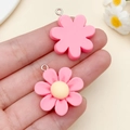 Pink and yellow resin flower charms with metal loops shown held by hand for DIY jewelry - Rose Red Resin Seven Petal Flower (24351) / 28x25x7mm