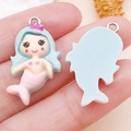 Cartoon mermaid resin pendant in light blue and pink, shown in hand for scale detail - Lake Blue Hair Mermaid (24484) / 29x17x6mm