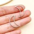 Pendientes de media luna plateada minimalista mostrados en los dedos para escala - Estilo Luna Mediano (T1837)