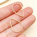 Golden teardrop stainless steel frames for DIY jewelry, held to show medium size scale - Waterdrop (T1852) / Gold