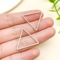 Eleganti orecchini a triangolo cavo in oro rosa mostrati sul dito per la misura - Stile Triangolo (T1860)