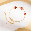 Detailaufnahme von goldenem Titanarmband mit roten Kristallblumen auf Steinhintergrund - Fünfblättriger Blumenstil (Red Bracelet #3)