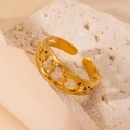 Détail d'une bague ajustable dorée avec cœurs ajourés sur une pierre beige texturée - Style Cœur Ajouré Continu (1) / Or