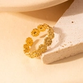 Makroaufnahme eines goldenen Sonnenblumenrings auf einem strukturierten Steinsockel - Gänseblümchen-Blumen-Cluster-Stil (BJGR0107)