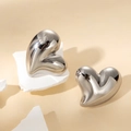 Macro shot of silver heart studs with polished mirror finish on white stone base - Silver Fluid Heart Style (#0121Y)