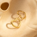 Detailed view of hollow heart-shaped gold-plated stainless steel earrings on a ceramic tray - Gold Hollow Heart Style (BJGE0634)