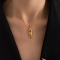 Macro detail of a golden seahorse pendant necklace on a model with premium metal texture - Seahorse Necklace