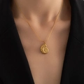Detailed view of a golden nautilus pendant necklace on a model with a black blazer - Conch Necklace