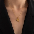 Close-up of a gold necklace with a fish-shaped pendant featuring textured wave details - Small Fish Necklace
