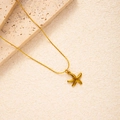 Detaillierte Nahaufnahme einer goldenen Seestern-Halskette auf cremefarbenem Stein - Oktopus Kette (BJGN0384)
