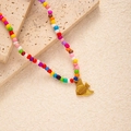 Detail of colorful beaded necklace with a golden fish pendant on a stone background - Fish Pendant (#0389)