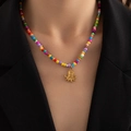 Detalle de collar de cuentas coloridas con colgante de pulpo dorado en fondo negro - Pulpo (Collar Cuentas De Colores)
