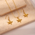 Elegant gold starfish jewelry set including necklace and earrings on a stone background - Starfish Set