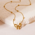 Elegant gold bow pendant necklace with beaded chain on a white marble stone surface - Necklace