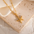 Macro shot of gold-plated starfish pendant necklace on textured stone and satin fabric - Starfish