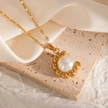 Detailed view of a gold chain with a large white pearl pendant on a silk and stone background - Wave Lace Base Style (JJN0078)