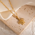 Detailed view of a gold turtle pendant necklace on a premium textured stone surface - Turtle