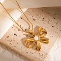 Detailed macro view of a 18k gold flower bow pearl necklace on elegant white silk fabric - Bowknot Style (JJN0190)