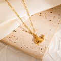 Detailed view of a gold whale pendant on a fine link chain over a textured stone surface - Whale