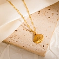 Detailed close-up of a golden scallop shell pendant on a fine necklace chain - Shell