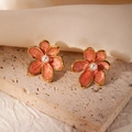 Detail view of orange floral enamel stud earrings with pearl center on silk fabric - Orange Flower (#0990)