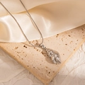 Detailed close-up of a silver conch shell pendant necklace on textured stone background - Steel